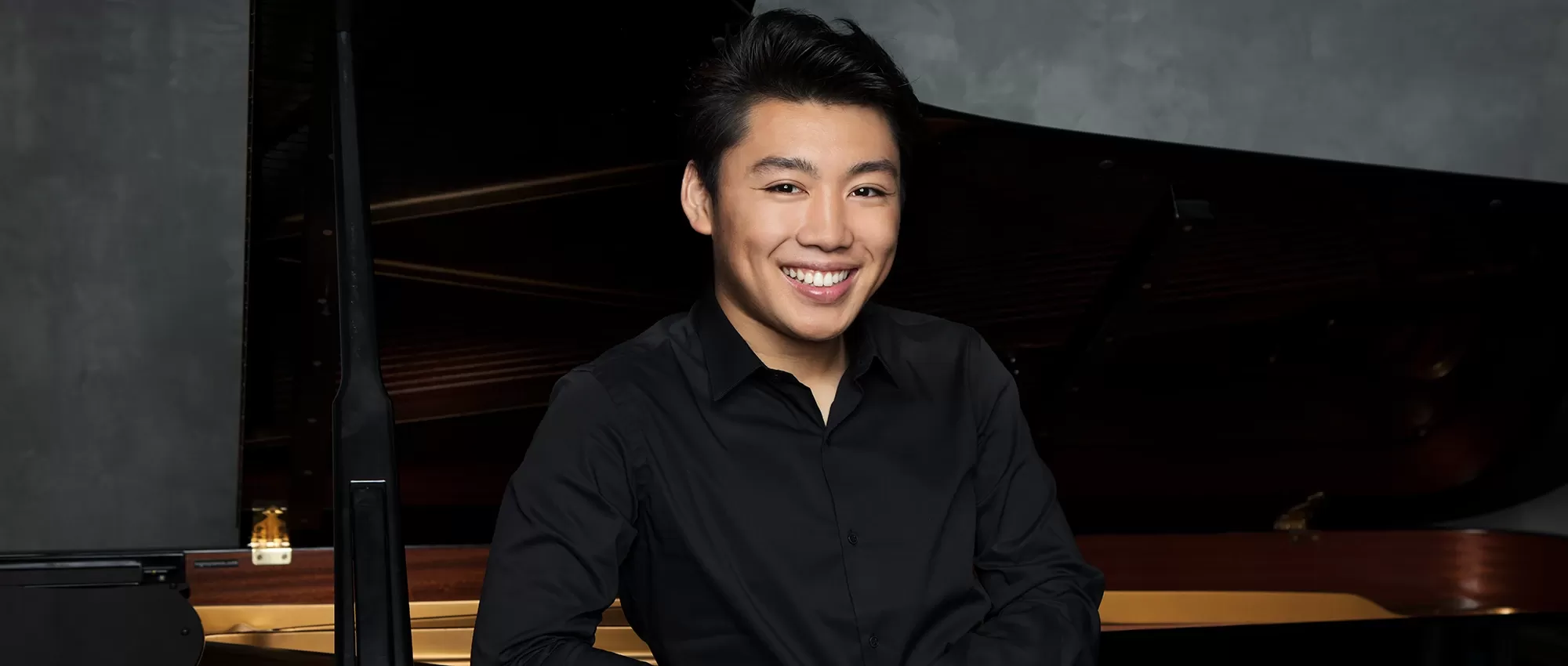 George Li in a blue shirt in front of the piano