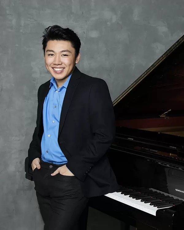 George Li in a blue shirt in front of the piano