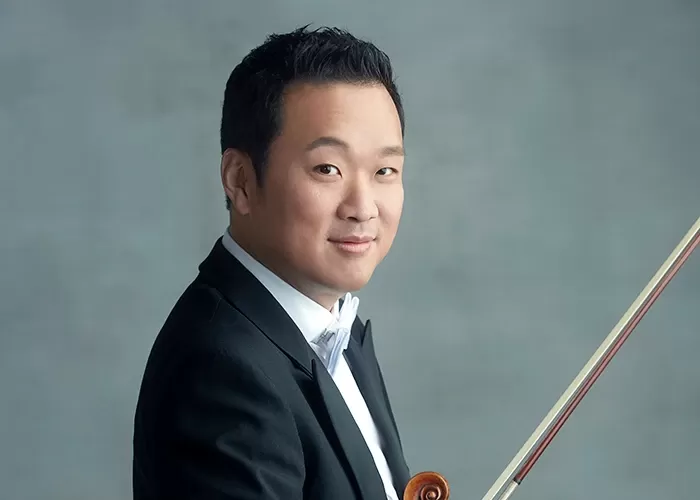 Dennis Kim hold his violin at his side