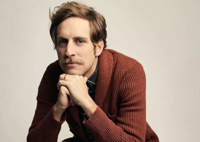 Ben Rector in a brown sweater with his hands held under his chin
