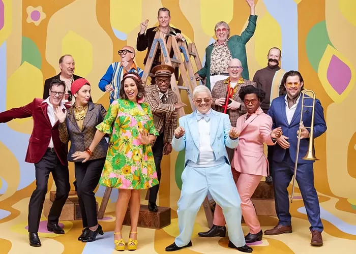 Members of the ensemble Pink Martini in front of a colorful background