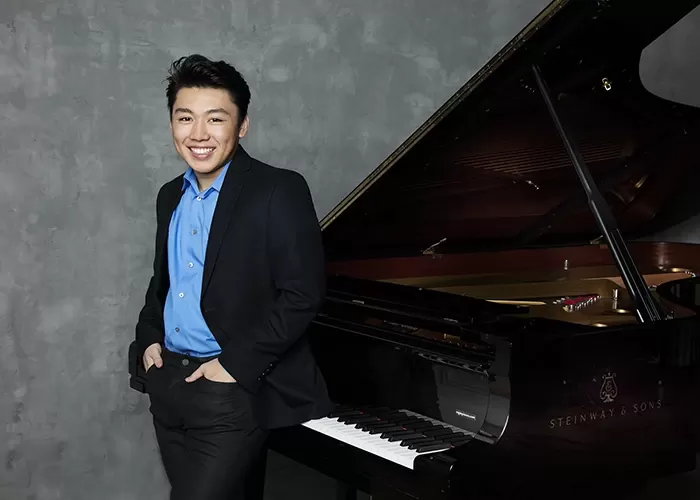 George Li in a blue shirt in front of the piano