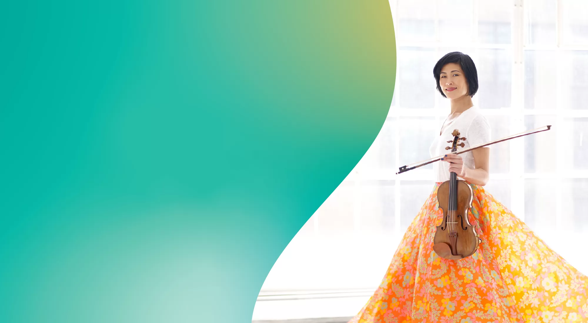 Jennifer Koh in a white blouse and colorful skirt holding her violin