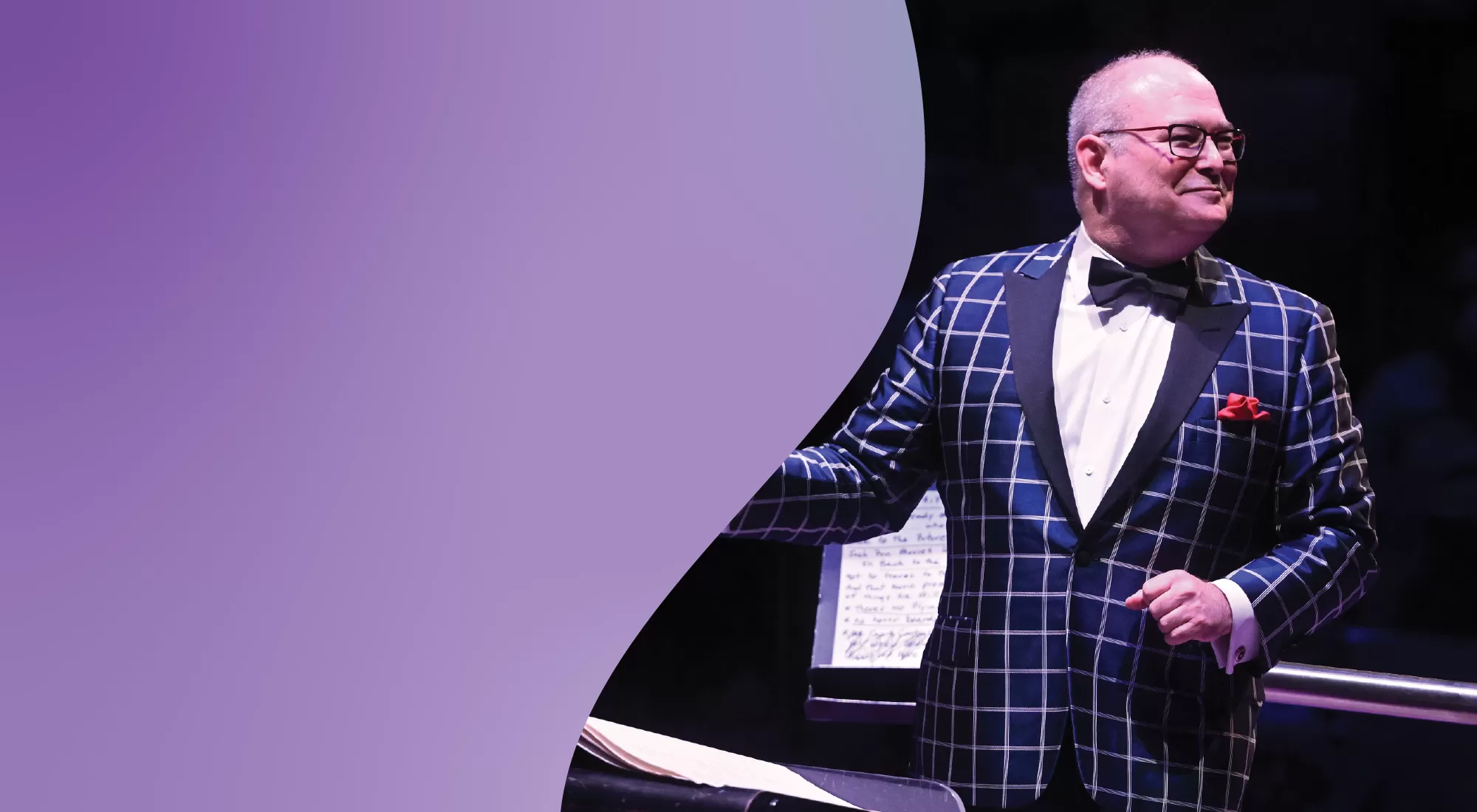 Guest conductor Stuart Chafetz wearing a plaid jacket and smiling while he conducts