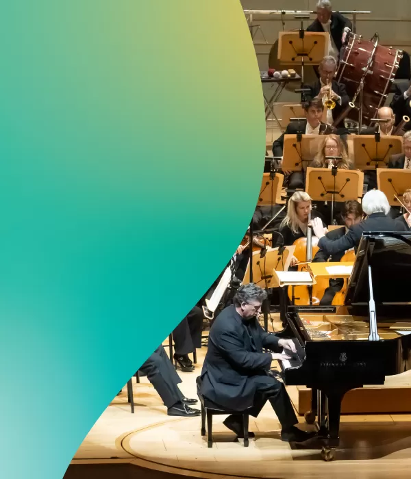 Pinist in black suit performing in front of the orchestra