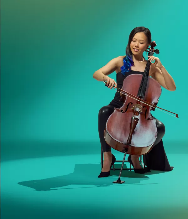 Young woman in black playing a cello against a green background