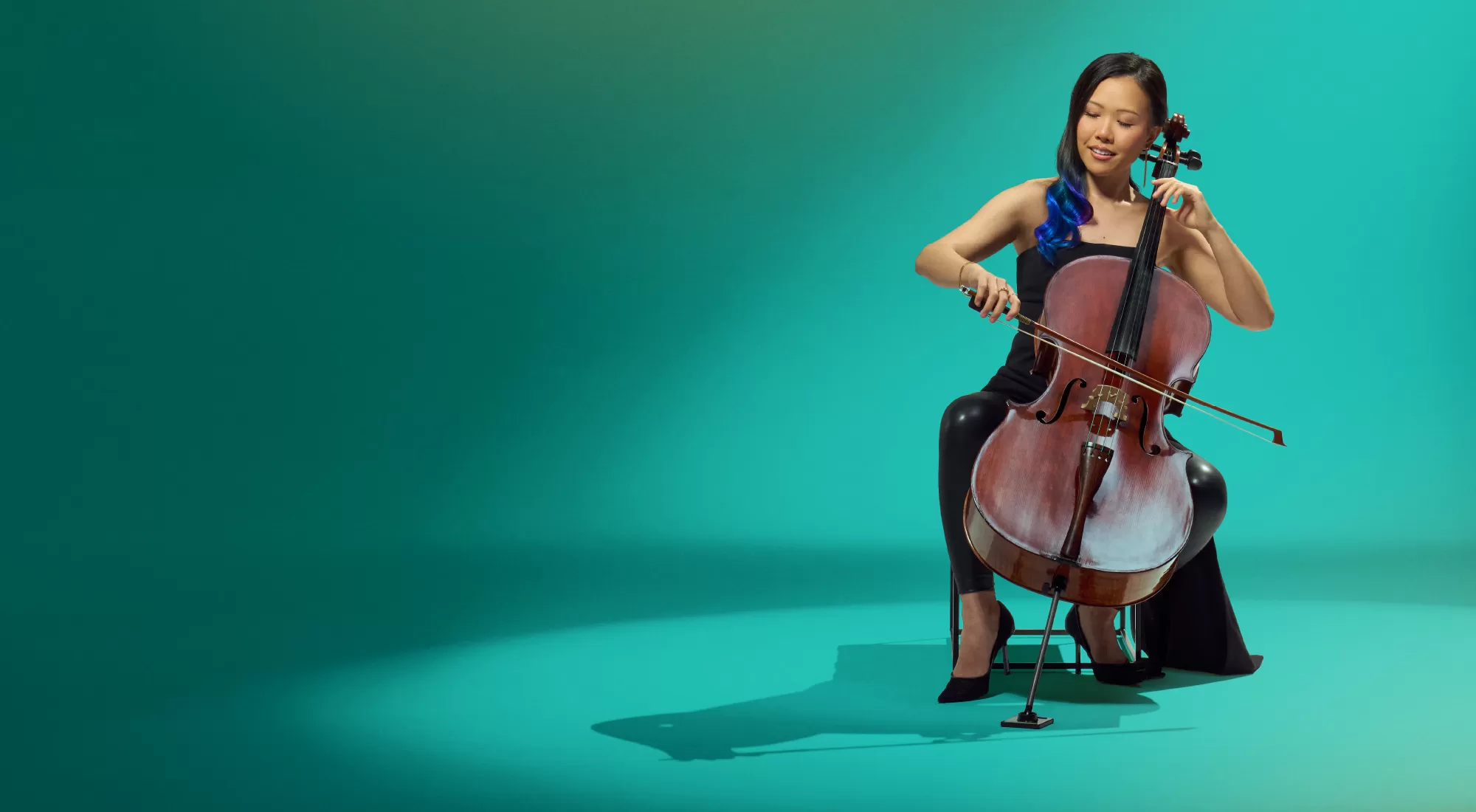 Woman playing a cello against a green background